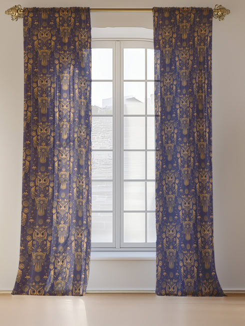 A sheer curtain panel featuring a repeating pattern of ornate golden owls surrounded by delicate floral designs and botanical elements on a deep navy background. The fabric has a fine linen-like texture with translucent qualities.